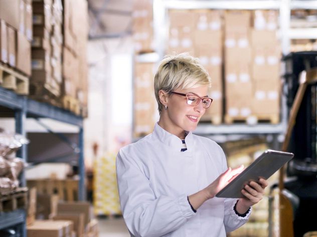 a woman in a warehouse typing into a tablet